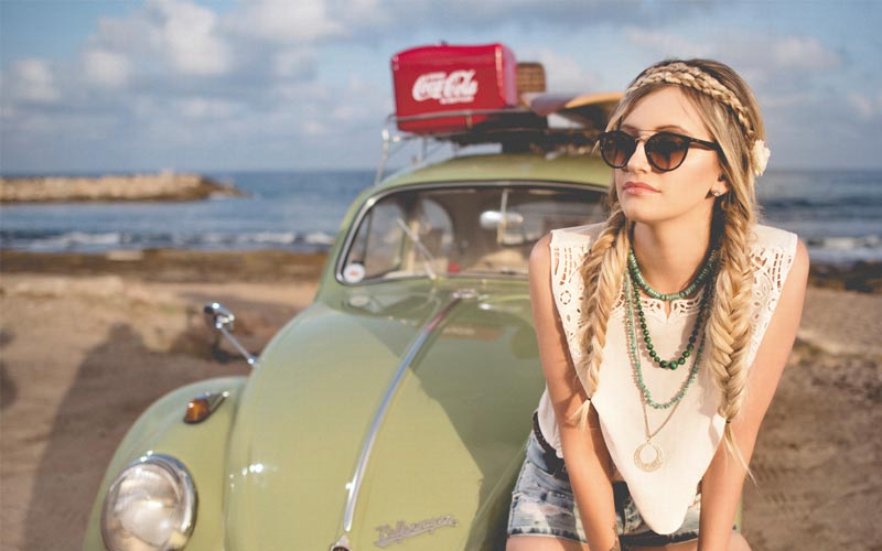 Woman sat on car at the beach